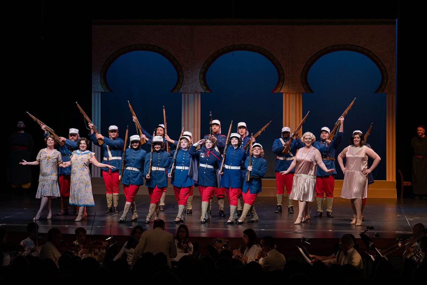 Legionnaires with rifles raised, the women of the company downstage