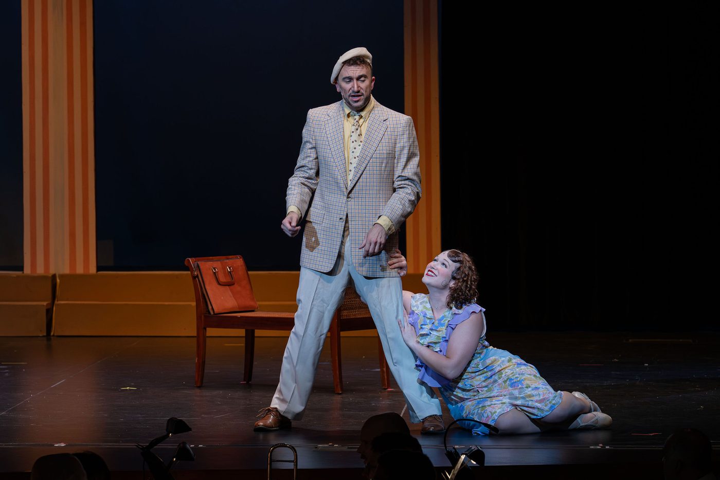 A comic beat downstage, one figure pleading at another's feet