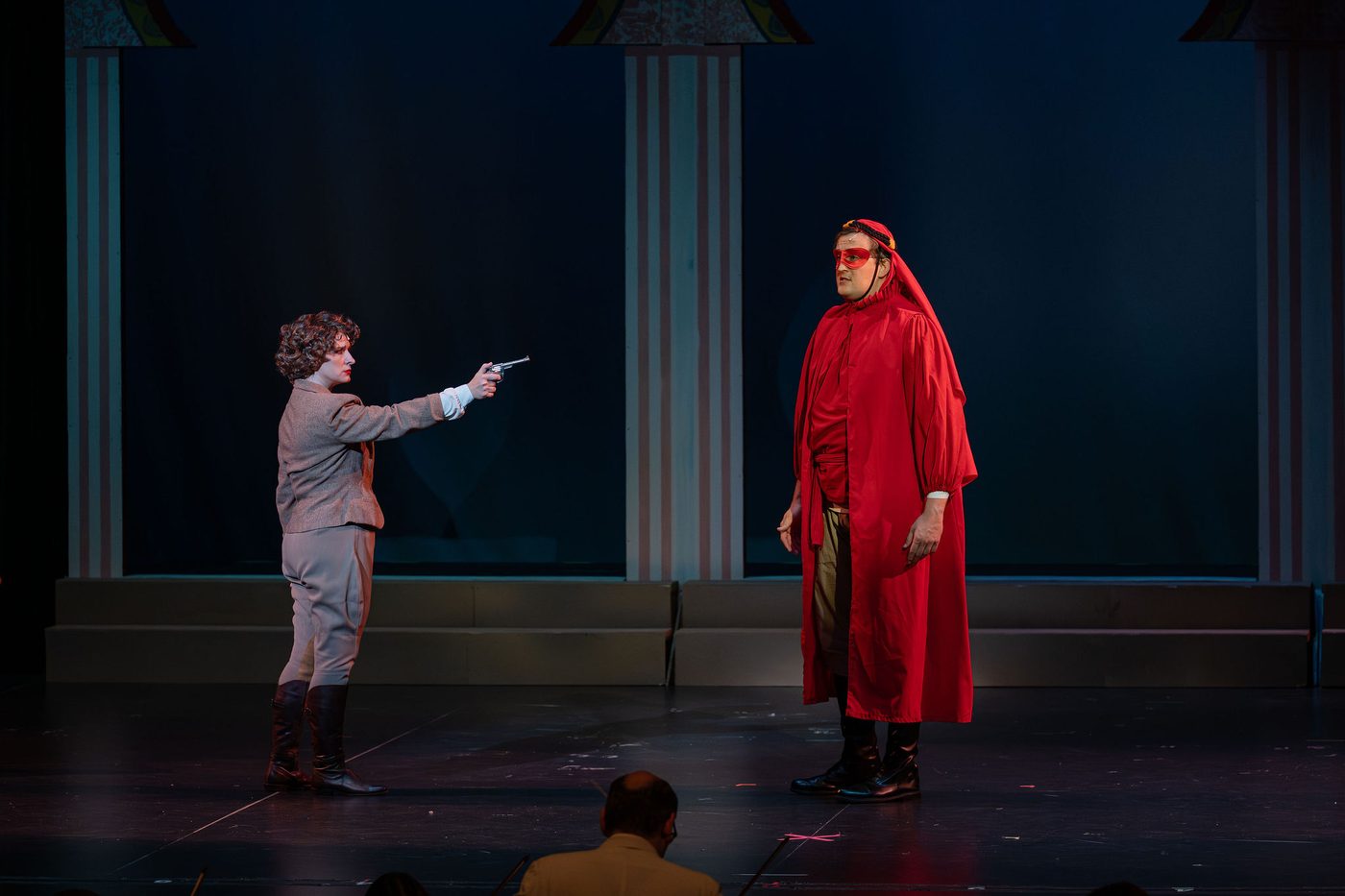 The Red Shadow in his hooded red robe, held at gunpoint