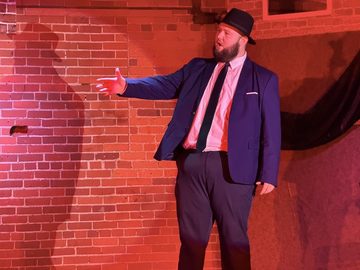 Blood Brothers, the Narrator on the red-lit set